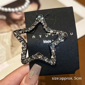 Detail of a 5cm silver star hair clip with rhinestones on a black display card