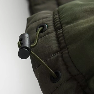 Detail of adjustable drawstring with black spring toggle on army green quilted fabric
