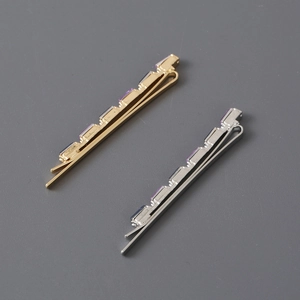Detail of gold and silver hair clips featuring rectangular purple rhinestone settings