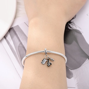 Detail view of silver music-themed snake chain bracelet with piano and saxophone charms