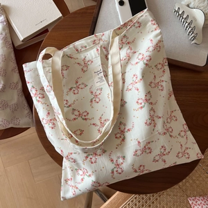 Vue détaillée du sac cabas en toile crème avec imprimé floral et étiquette en tissu interne