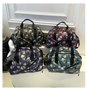 Detail view of large travel bags in four skull and rose prints with durable handles