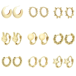 Set of nine golden twist earrings with rabbit and star studs on white background