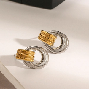 Close-up of geometric two-tone stainless steel earrings with polished gold and silver finish