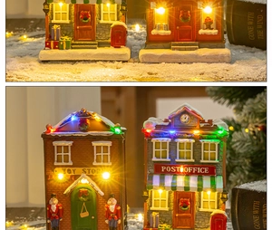 Detail view of glowing Christmas resin house models with LED lights and snow-covered roofs