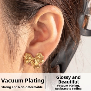 Detail view of a gold ribbon bow stud earring with rich pleated texture and metallic luster