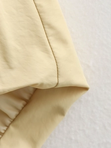 Détail de couture fine et texture de tissu polyester abricot lisse sur l'ourlet du gilet