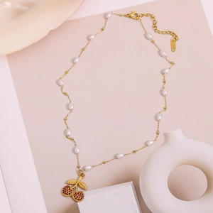 Detail of 18K gold-plated chain featuring white pearls and a red cherry pendant charm