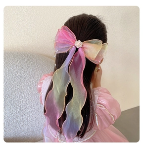 Detail of a large gradient mesh bow hair clip with pearls and long streamers on a girl