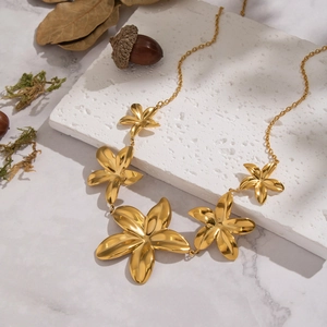 Elegant gold flower pendant necklace with five blooms on a natural marble stone display