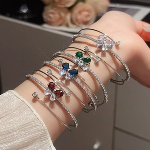 Dettaglio dei bracciali a farfalla multistrato con pietre di zircone colorate al polso