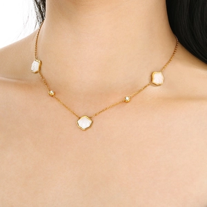 Elegant gold necklace with white hexagonal shell pendants and beads on a model