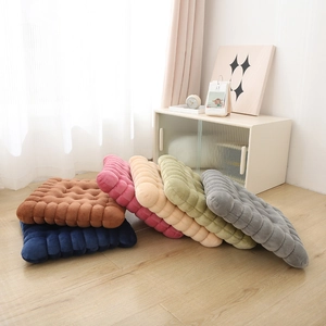 Thick biscuit-shaped floor cushions in various colors arranged on light wood flooring