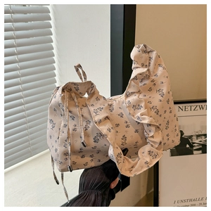 Detail of floral fabric texture and ruffled shoulder strap on the cream underarm bag