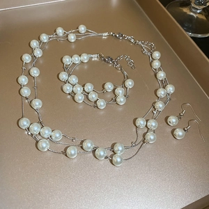 Elegant multi-layer pearl necklace bracelet and earrings set on champagne gold tray