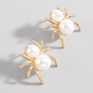 Macro shot of spider-shaped gold earrings featuring two white imitation pearls