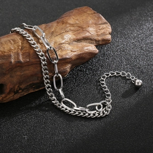 Detail of silver layered bracelet with curb and paperclip chains on a rustic wood piece