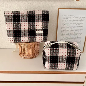 Macro shot of red plaid wool cosmetic bag set showing textured fabric and brand label