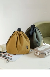 Detail of large waterproof drawstring lunch bags in ginger and olive green nylon fabric