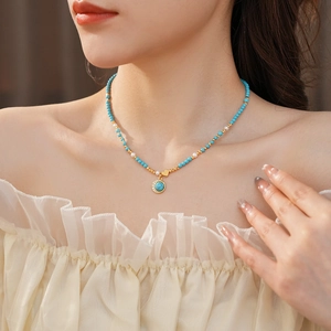 Détail du collier pendentif turquoise cœur sur mannequin avec perles et touches dorées