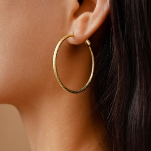 Close-up of matte gold geometric hoop earring on a model for a stylish commute look