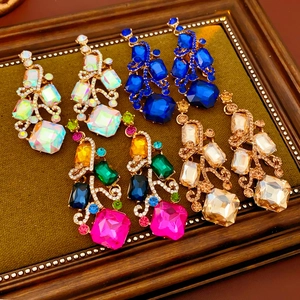 Close-up of vintage square stud earrings with colorful gemstones and rhinestones in gold setting