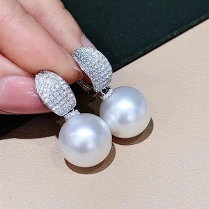 Detalle de pendientes de perlas de lujo con tachuelas ovaladas de cristales pavimentados