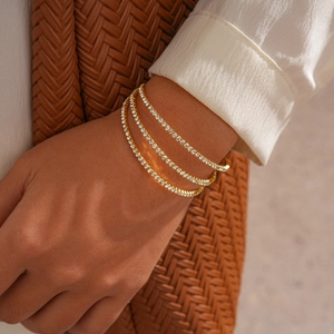 Close-up of gold-plated triple-layered tennis bracelet set with zircon stones and rope details