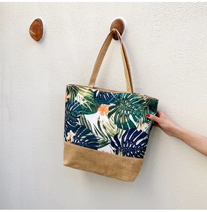 Detail of canvas tote bag featuring tropical palm leaf prints and woven texture base