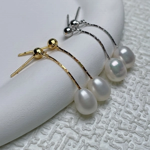 Macro shot of elegant white teardrop pearl earrings in gold and silver metal finishes