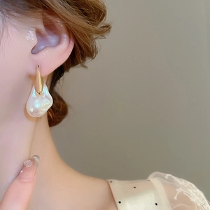 Dettaglio di un orecchino in oro 18 carati con perla barocca indossato da una modella