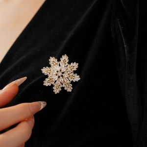 Macro shot of gold plated snowflake brooch with sparkling cubic zirconia on black velvet