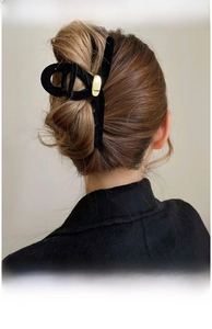 Gros plan d'une grande pince à cheveux en velours noir avec plaque dorée sur chignon