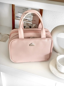 Pink matte PU leather cosmetic bag with dual handles and metal logo on white shelf