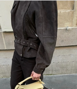 Detail of dark brown suede biker jacket featuring a matching eyelet belt and metal hardware
