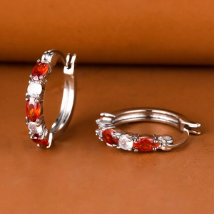 Detail of silver huggie earrings with alternating oval red and white zircon stones