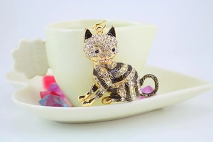 Detail of a golden cat pendant encrusted with clear rhinestones and black enamel accents
