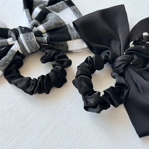 Macro detail of checkered and skull pattern bow scrunchies on white wooden texture