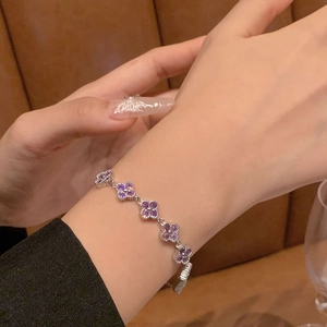 Close-up of sparkling purple zircon flower chain bracelet worn on a wrist over a leather background