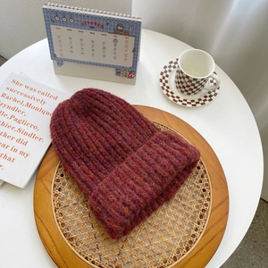 Close-up of thick knit wine red beanie on a tray with warm winter home accessories
