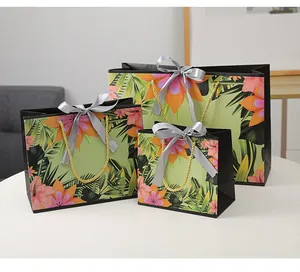 Three premium floral gift bags in varied sizes with gold handles and satin bow details