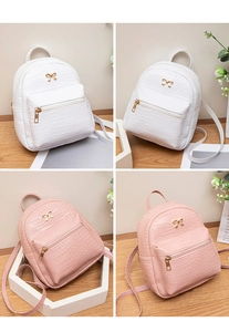 Detail of crocodile pattern mini backpack with golden bow accent in white and pink