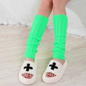 Detail of neon green cable knit leg warmers showing textured twist pattern on calf