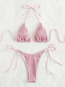 Dettaglio del bikini rosa chiaro plissettato con lacci su fondo di pelliccia bianca