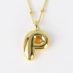 Macro shot of 3D bubble style letter P gold pendant necklace with minimalist beaded chain