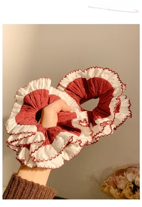 Close-up of dual red and white pleated scrunchies with delicate ruffled lace edges