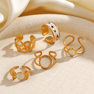 Set of five gold titanium steel rings with mother of pearl inlay on beige fabric