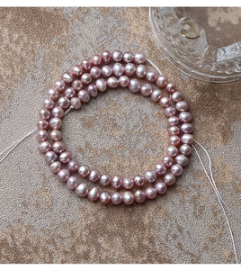 Macro detail of natural pink-purple freshwater pearls strands on a gold textured background