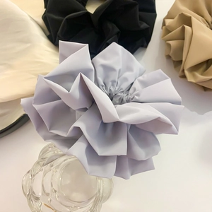 Detail shot of a grey ruched floral scrunchie in soft faux leather with a satin finish