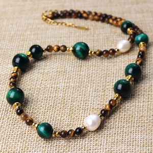 Detail of beaded necklace with tiger eye stone, green malachite, and white pearls on linen